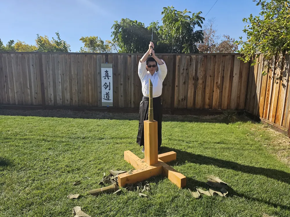 A student raising the sword overhead at the tameshigiri stand